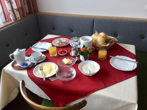 una mesa con un mantel rojo con comida. en Pension Vocario, en Pfarrwerfen