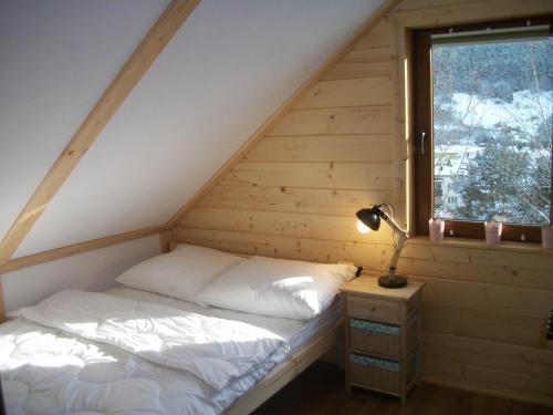 Łóżko w drewnianym pokoju z oknem w obiekcie Domek Stokrotka w mieście Krynica Zdrój