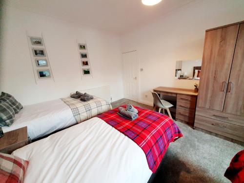 a bedroom with two beds and a desk and a desk at Station Apartment in Bellshill