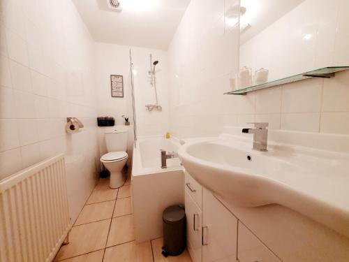 a white bathroom with a sink and a toilet at Station Apartment in Bellshill