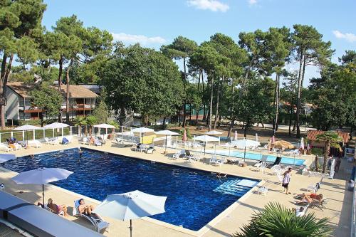 a swimming pool with umbrellas and people sitting around it at Azureva Ronce les Bains in Ronce-les-Bains