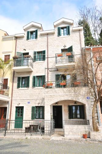 a large stone building with green shuttered windows at Apartments Jelena Skver in Herceg-Novi