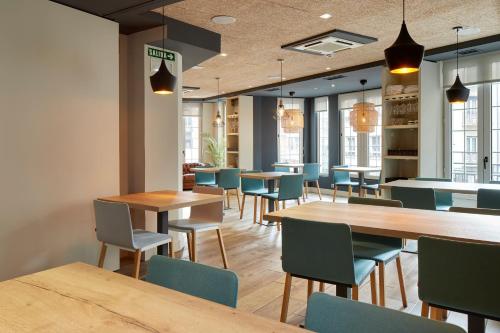 un restaurante con mesas de madera y sillas azules en Hotel Avenida en Pamplona