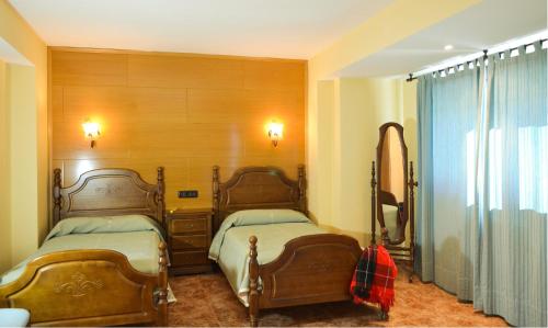 1 dormitorio con 2 camas y espejo en Hotel Suiza, en Bronchales