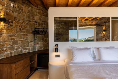 a bedroom with a bed and a stone wall at Mykonos AG Villas in Ftelia Beach in Elia