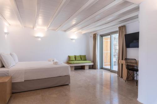 a white bedroom with a bed and a window at Mykonos AG Villas in Ftelia Beach in Elia