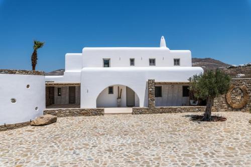 a white house with a palm tree in front of it at Mykonos AG Villas in Ftelia Beach in Elia