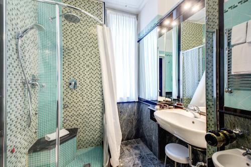 a bathroom with a glass shower and a sink at Brunelleschi Hotel in Milan