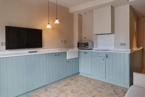 a kitchen with blue cabinets and a flat screen tv at Pamplonapartments Pozo Blanco in Pamplona