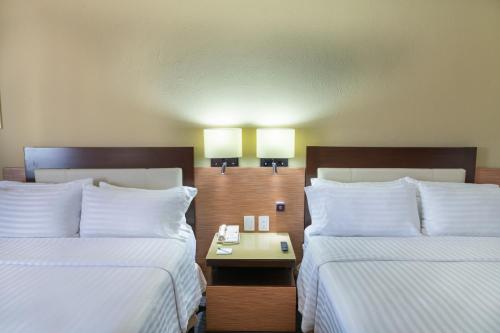 ein Hotelzimmer mit 2 Betten und einem Tisch dazwischen in der Unterkunft Holiday Inn Guadalajara Select, an IHG Hotel in Guadalajara