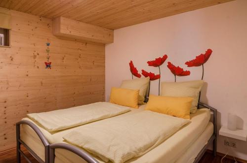 two beds in a room with red flowers on the wall at Ferienwohnung Untergeschoss in Überlingen