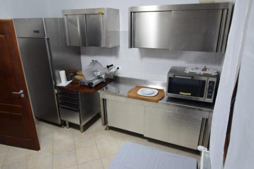 a kitchen with stainless steel appliances and a microwave at Agropensiune CASA SONIA in Băcia