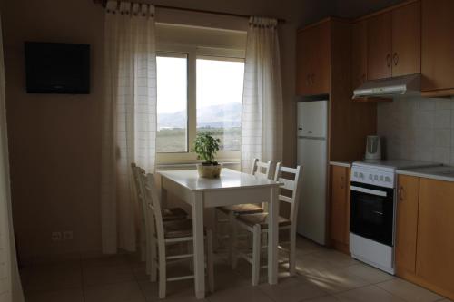 cocina con mesa, sillas y ventana en Argilos Apartments, en Frangokastello