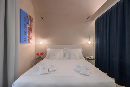 ein Schlafzimmer mit einem großen weißen Bett mit zwei Kissen in der Unterkunft Sikelia Suites in Noto