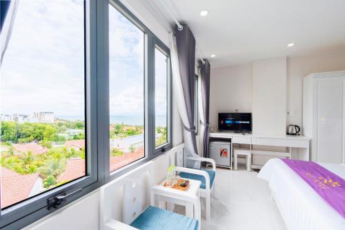 a bedroom with a bed and large windows at Sen Hotel Phu Quoc in Phu Quoc