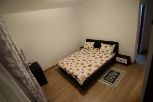 um quarto com uma cama com uma colcha e almofadas em Agropensiune CASA SONIA em Băcia