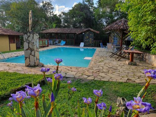 a swimming pool in a yard with purple flowers at Capricho Asturiano in Santo Antônio do Leite