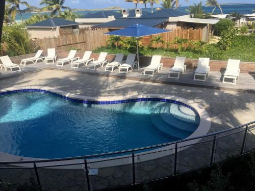 a swimming pool with chairs and umbrellas at Orient Beach Hotel in Orient Bay