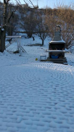 a snow covered ground with a bird house in the background at Honey hill apartment Fruska Gora in Čerević