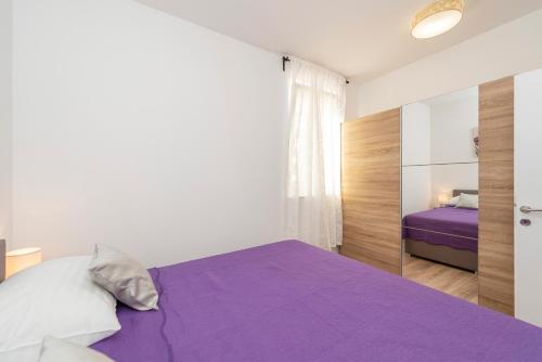 a bedroom with a purple bed and a mirror at Villa Eni apartments 2 in Mandre
