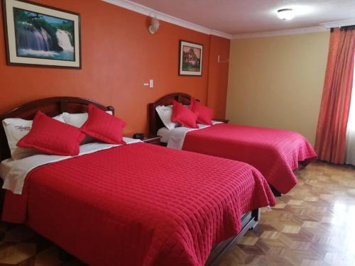 2 camas en una habitación de hotel con paredes rojas en Hotel Allegria, en Quito