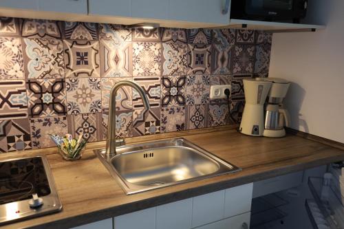 un comptoir de cuisine avec évier en acier inoxydable et carrelage dans l'établissement CT-Apartments, à Kerken