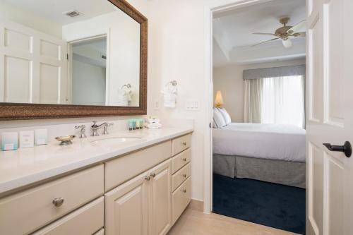 baño con lavabo, espejo y cama en Bellasera Resort en Naples