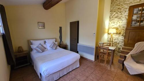 a bedroom with a bed and a table and a chair at Logis Hôtel La Bastide Saint Bach in Suze-la-Rousse