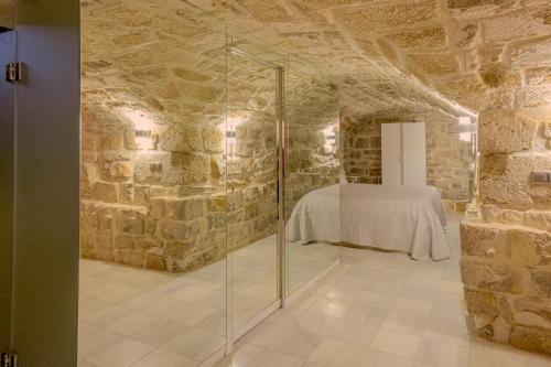 a room with a glass shower in a stone wall at Apartamentos “Quotidianum” in Úbeda