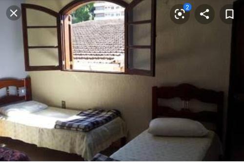two beds in a room with a window and a window at Pousada Terra das Águas in São Lourenço