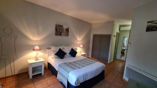 a bedroom with a bed and a night stand with a lamp at Logis Hôtel La Bastide Saint Bach in Suze-la-Rousse