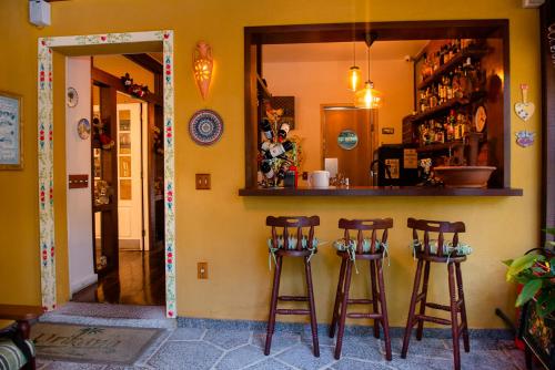 a kitchen with three bar stools in a room at Urikana Boutique Hotel in Teresópolis
