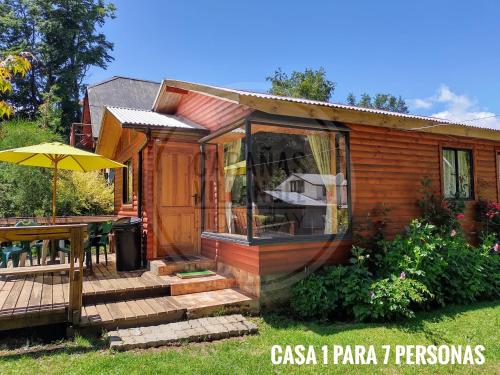 a cabin with a deck and a table and an umbrella at Cabañas Villangel Licanray in Licán Ray