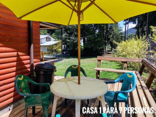 a table and chairs under an umbrella on a deck at Cabañas Villangel Licanray in Licán Ray
