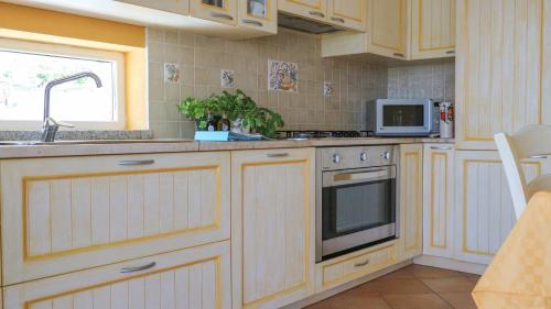 Una cocina con gabinetes blancos, un fregadero y un microondas. en Aria, en Budoni