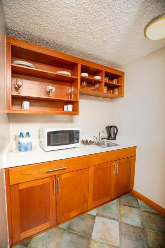 a kitchen with wooden cabinets and a microwave at Le Plaza Hotel in Port-au-Prince
