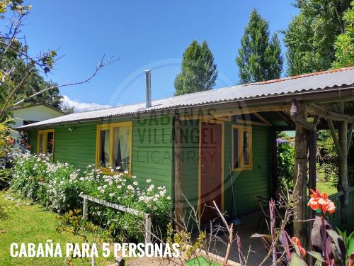 a green cottage with flowers in front of it at Cabañas Villangel Licanray in Licán Ray