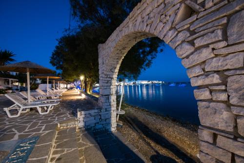 a stone wall next to the water at night at Ostria Studios & Apartments in Aliki