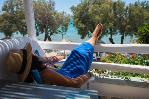 a woman laying on a porch with her feet on a fence at Ostria Studios & Apartments in Aliki