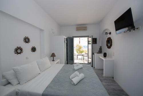 a white bedroom with a large bed with white pillows at Ostria Studios & Apartments in Aliki