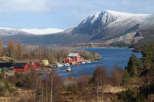 a small town on a river with a snow covered mountain at Skomakergarden in Ulsteinvik