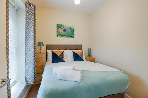 a bedroom with a large bed with a blue blanket at Perfect Location with Parking - Jersey House - TV in every Bedroom! in Swansea