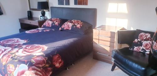 a bedroom with a bed and a chair and a dresser at Plumpton House in Ashford