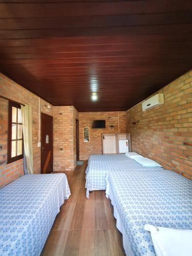 a room with two beds and a brick wall at Pousada do Riacho in Barreirinhas