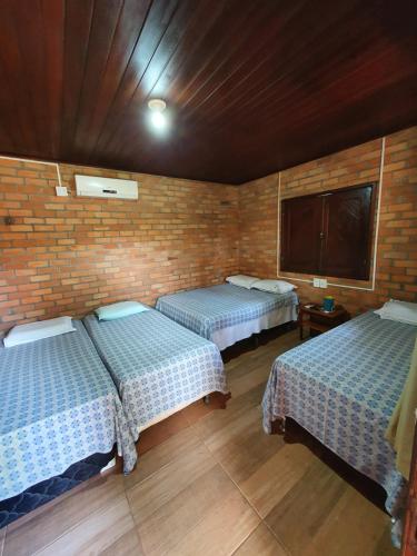 a room with two beds and a brick wall at Pousada do Riacho in Barreirinhas