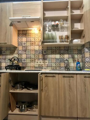 a kitchen with wooden cabinets and tiles on the wall at Вілла Лісова комфорт in Skhidnitsa