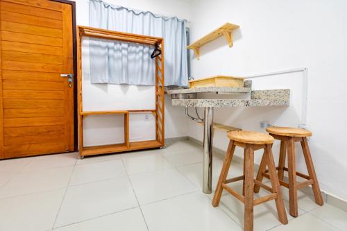a kitchen with a sink and two stools at Encanto da Praia hotel pousada in Natal