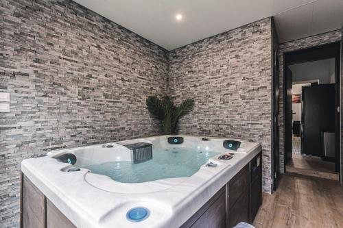 a hot tub in a room with a brick wall at Art Déco Gare & Spa in Reims