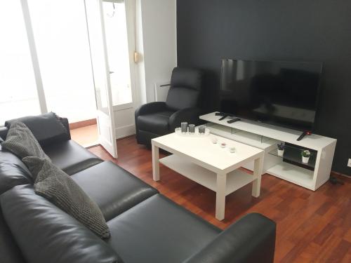 a living room with a couch and a table and a tv at FRANPAVI Aviles in Avilés