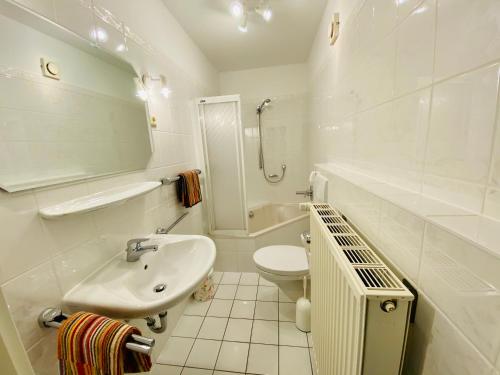 a white bathroom with a sink and a toilet at Villa Caprivi - Ferienwohnung E2 in Heringsdorf